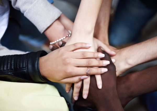 Close up top view of young people putting their hands together. Friends with stack of hands showing unity and teamwork.